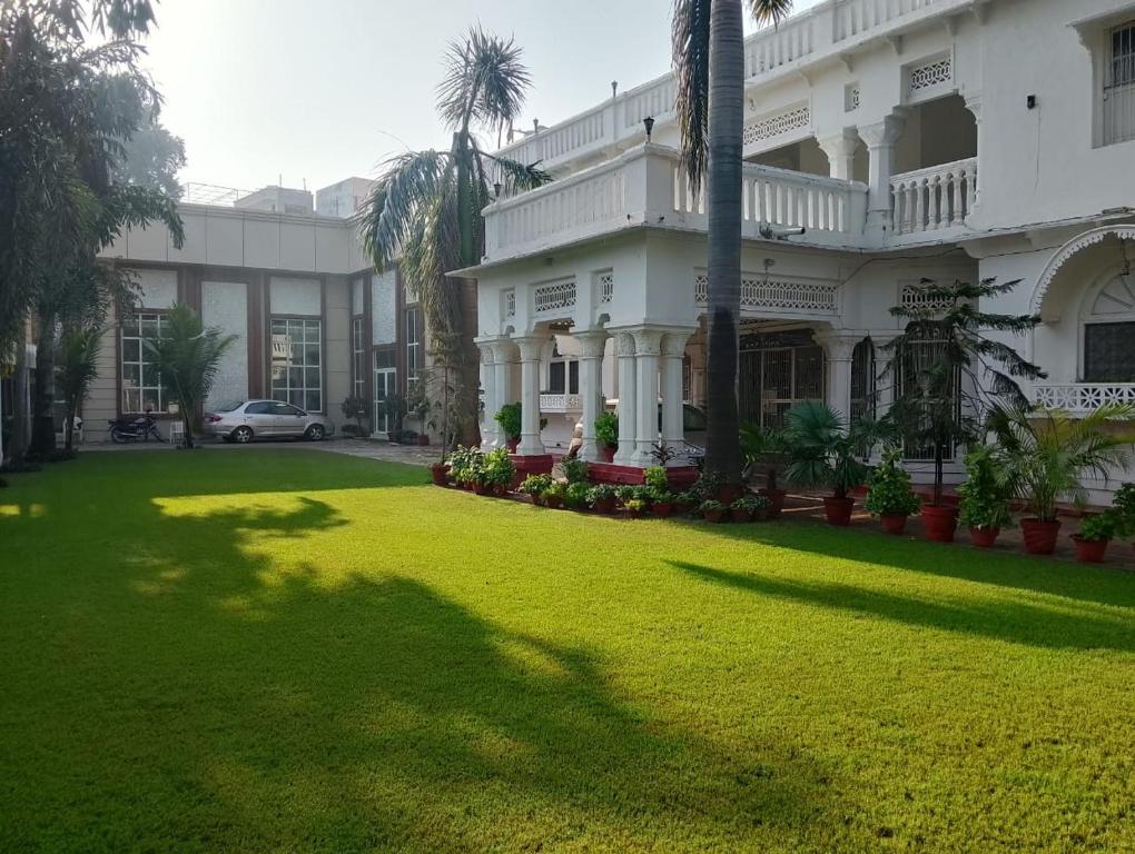 un grand bâtiment blanc avec une pelouse verte devant lui dans l'établissement Colonial Heritage Bungalow, à Prayagraj