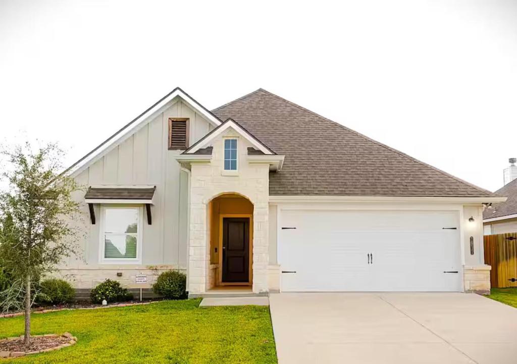 a white house with a garage at Luxury Home Near Kyle Field & Expo Center in Bryan