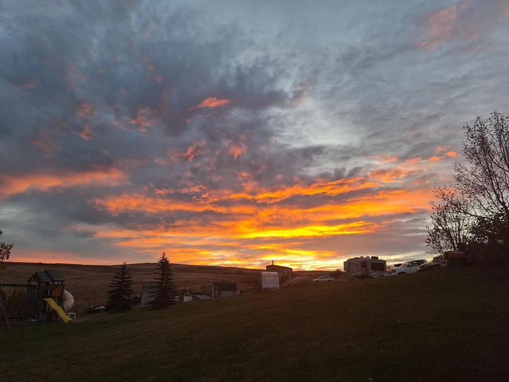 a sunset in a field with a cloudy sky at Misty Ridge Retreat B&B in Foothills