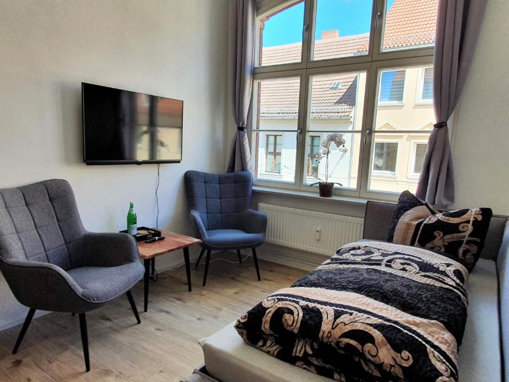 a living room with a bed and two chairs and a tv at Hogulu - klein und fein in der Altstadt, Appartement 10 in Brandenburg an der Havel