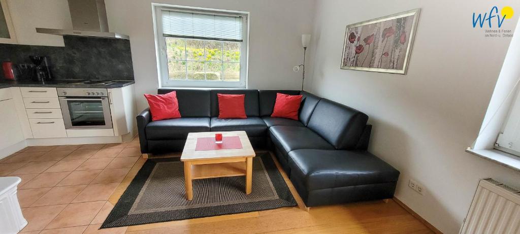 Una sala de estar con un sofá de cuero negro y una mesa. en Fuhrmannshof Ferienwohnung Cassen, en Juist