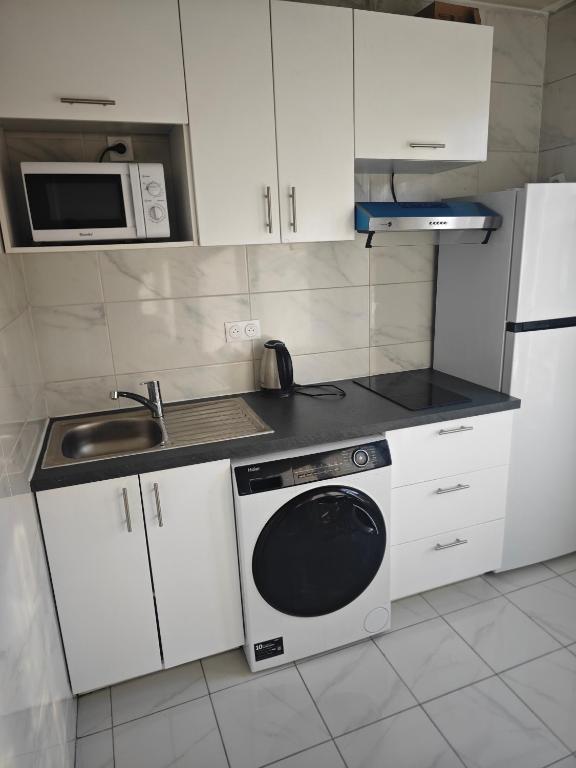 La cuisine est équipée de placards blancs, d'un four micro-ondes et d'un lave-vaisselle. dans l'établissement Le Anatole, à Aubervilliers