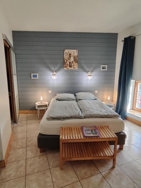 a bedroom with a large bed with a blue wall at La ferme aux chats in Formigny