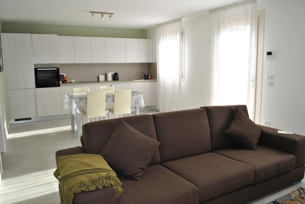 a living room with a brown couch and a kitchen at Appartamento La Bussola in Còvolo