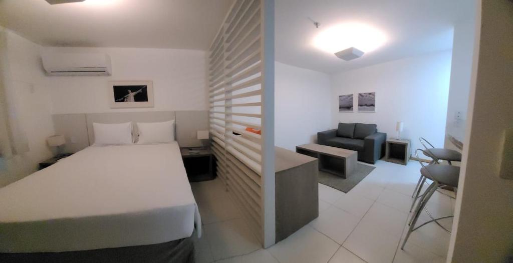 a bedroom with a bed and a couch and a chair at Promenade Prime Itaboraí in Itaboraí