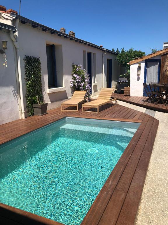 - une piscine sur une terrasse en bois avec des chaises dans l'établissement MAISON SPACIEUSE LA ROCHELLE, à La Rochelle