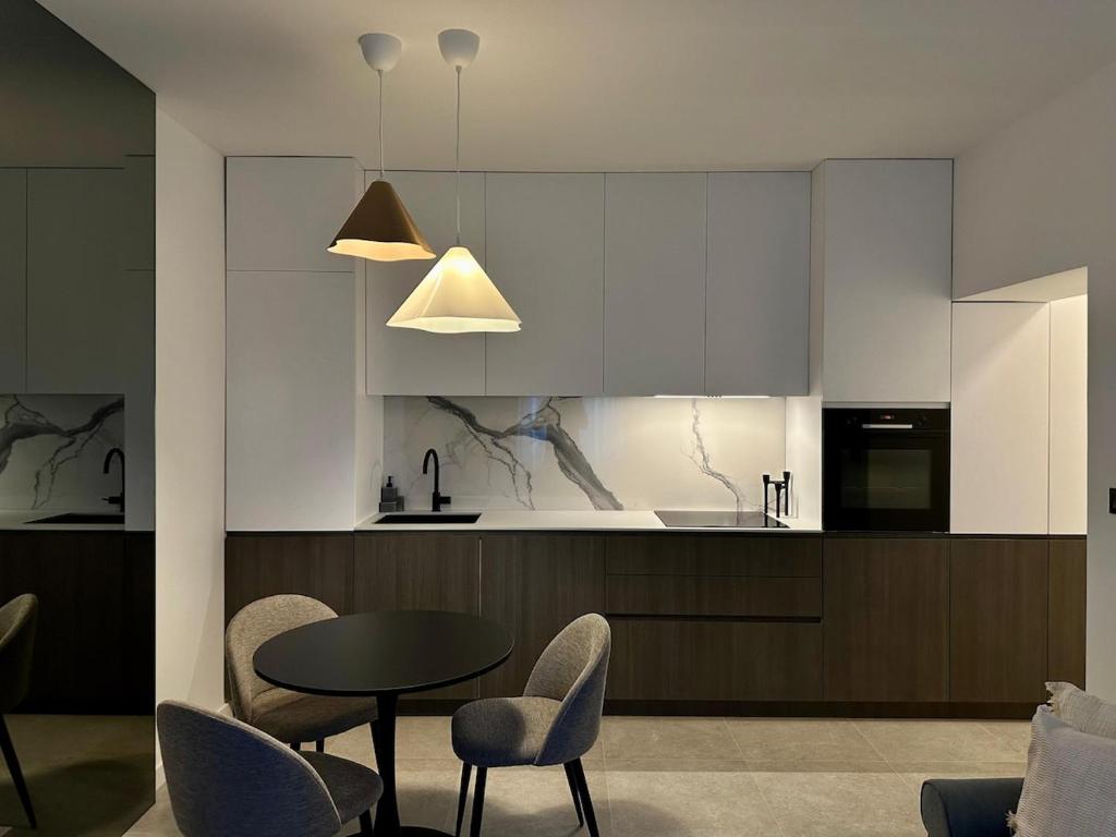 Una cocina con gabinetes blancos y una mesa y sillas. en Miol apartment, en Kaštela