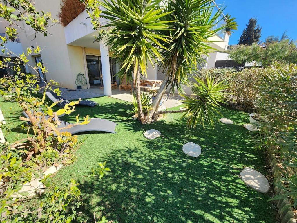 une cour avec un palmier et une maison dans l'établissement New Le Farnienté, à Bandol