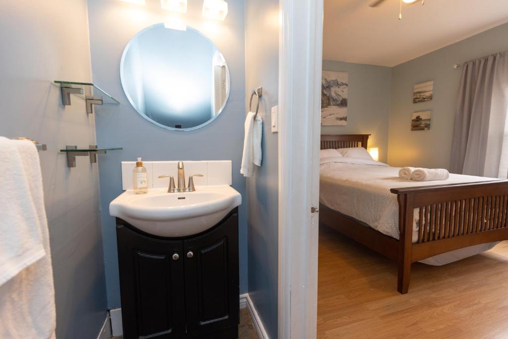 a bathroom with a sink and a bed with a mirror at HI Charlottetown Backpacker's Inn in Charlottetown
