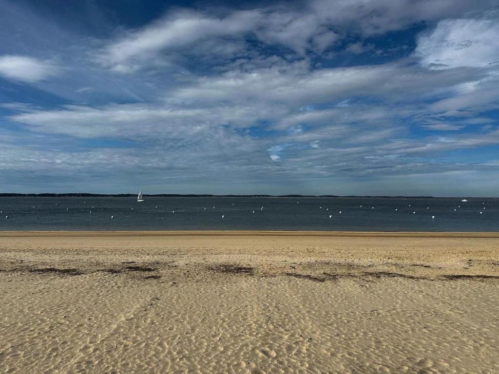 une plage de sable avec un voilier dans l'eau dans l'établissement Résidence Caravelle - Arcachon Pereire - Studio avec accès direct à la plage MAE-8344, à Arcachon