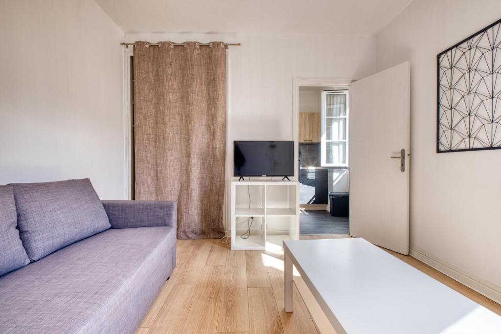 un salon avec un canapé et une télévision dans l'établissement Le deuxième ciel de la vertu, à Périgueux