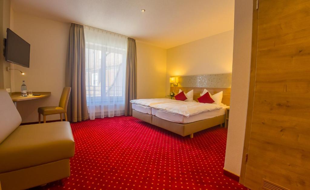 a hotel room with a bed and a red carpet at Hotel Restaurant Bären in Isny im Allgäu