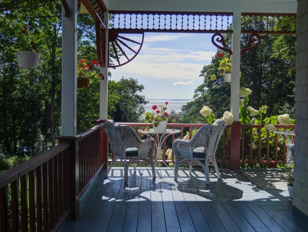 a porch with two chairs and a table at Victorian by the Sea in Lincolnville