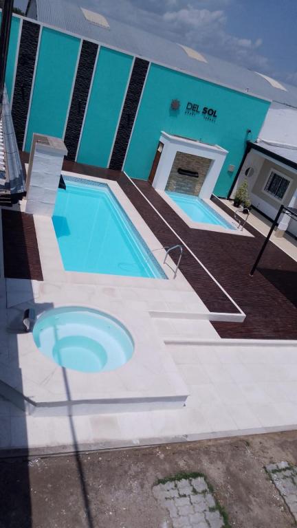 two swimming pools in front of a building at DEL SOL APARt TERMAL V in Termas de Río Hondo