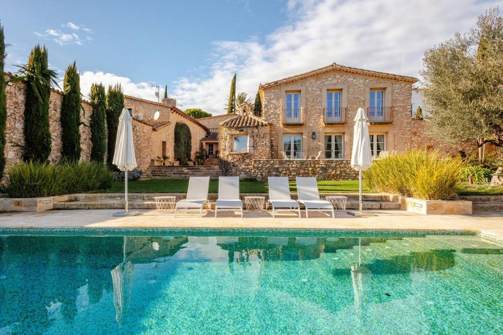 a house with a swimming pool and two umbrellas at Casa de Piedra ubicada en el exclusivo wine village de Viladellops, te ofrece una experiencia única, donde el lujo y la tradición se fusionan en un entorno natural privilegiado in Viladellops