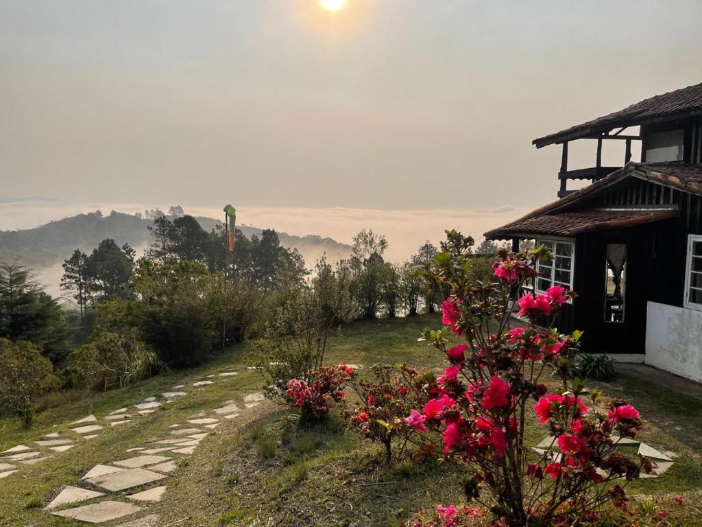 ein Haus mit rosa Blumen am Straßenrand in der Unterkunft Chalé acima das nuvens - Serra da Bocaina in São José do Barreiro