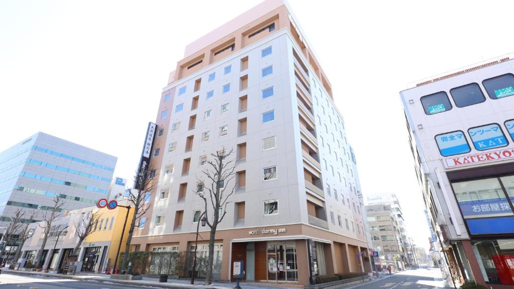 Un edificio alto y blanco en una calle de la ciudad. en Dormy Inn Matsumoto, en Matsumoto