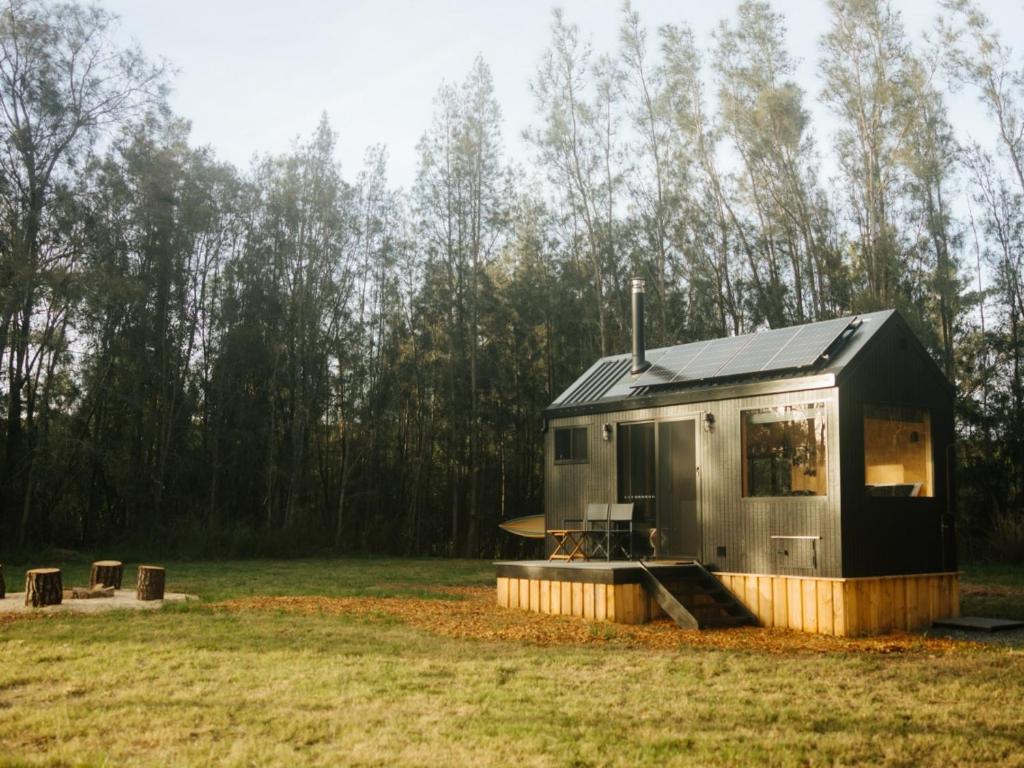 a tiny house sitting on top of a field at Secluded Off-Grid Cabin in the Hunter Valley - Leo in Pokolbin