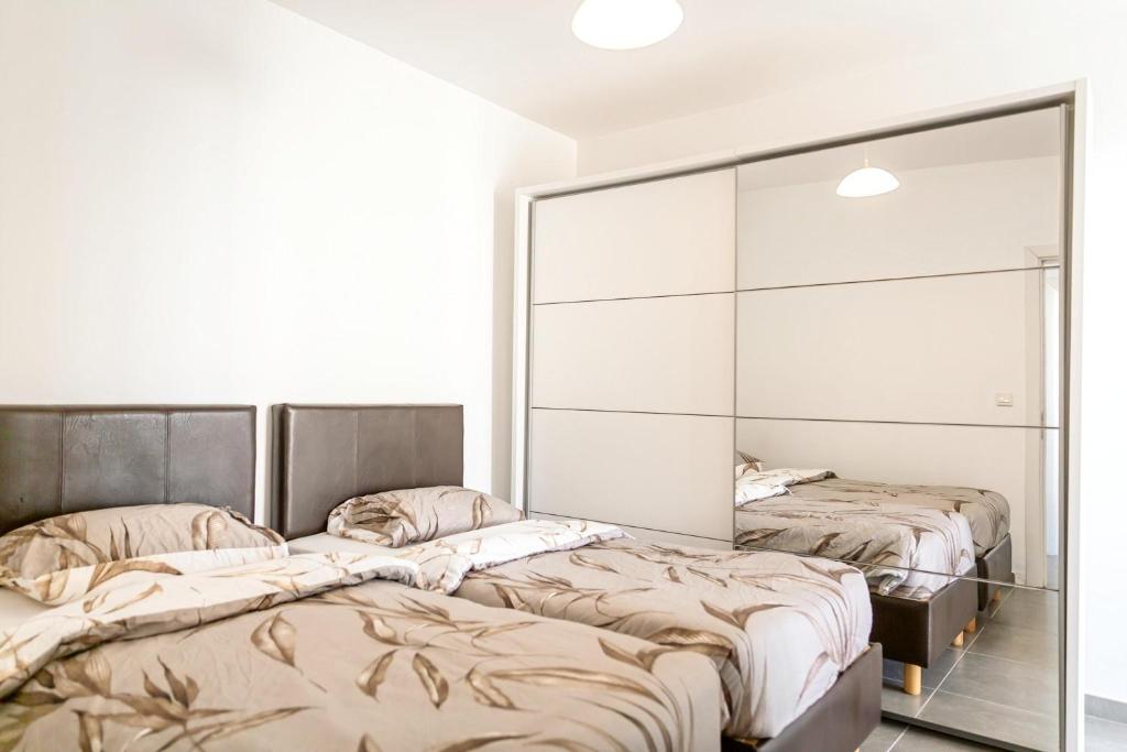 two beds in a room with a mirror at Luxury 3 Bedroom Apartment in Sliema - Walk to Beach & Dining in Sliema