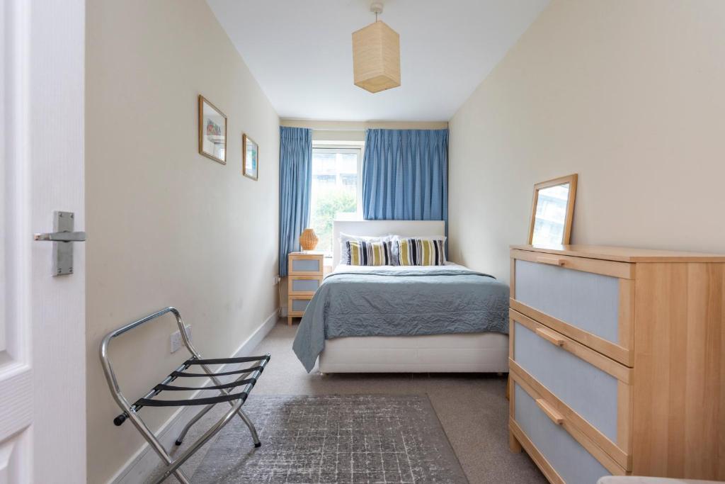 a bedroom with a bed and a chair and a window at Battersea Power Station Apartment in London