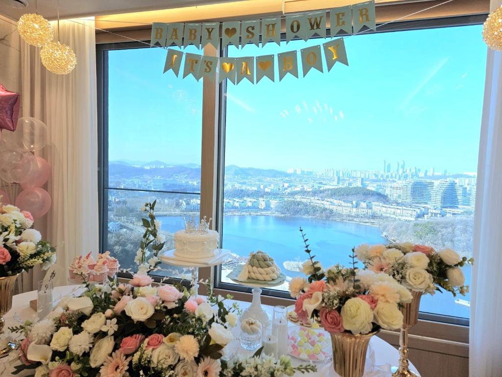 a table with a cake and flowers in front of a window at 동탄호수뷰하버 룸3 in Hwaseong