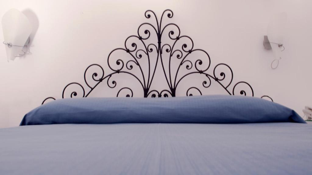 a bed with a blue pillow and a black headboard at Albergo 'La Vigna' in Procida