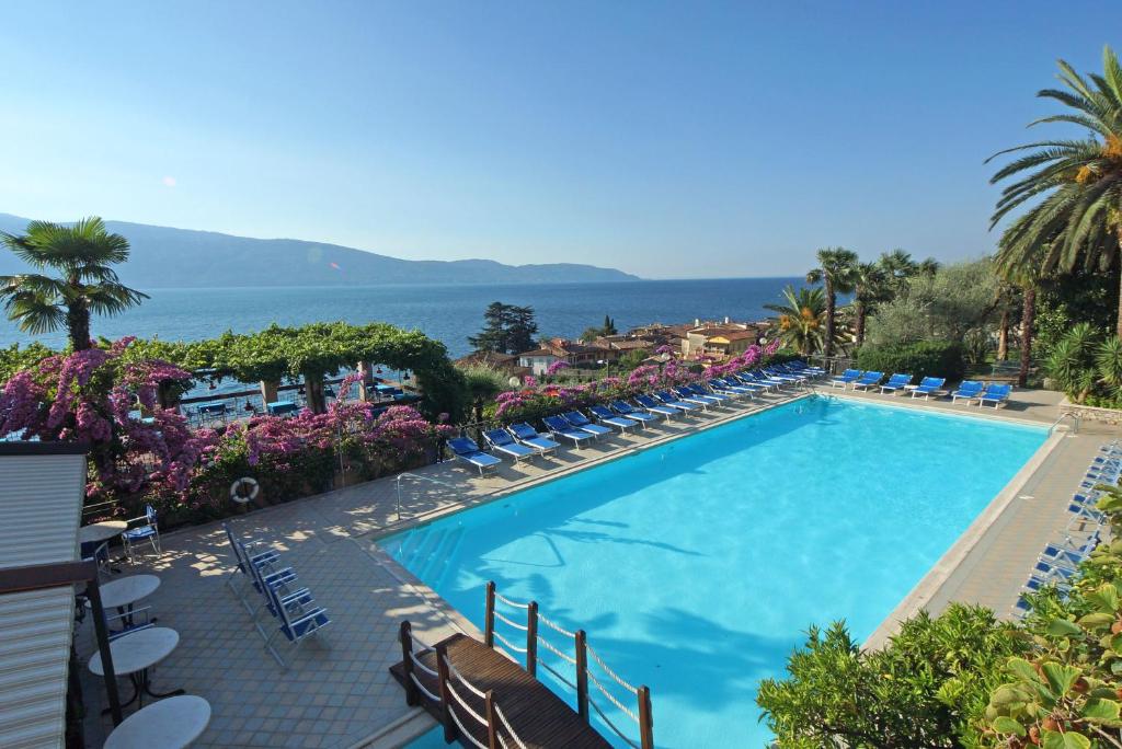 a swimming pool with chairs and the ocean in the background at Hotel Palazzina in Gargnano