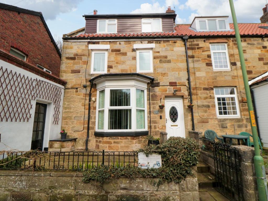 ein altes Backsteinhaus mit weißer Tür in der Unterkunft Florence Cottage in Saltburn-by-the-Sea