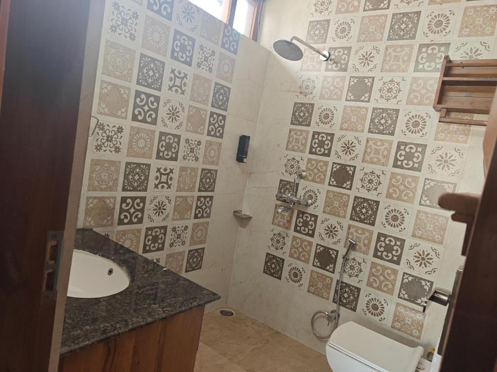 a bathroom with a sink and a toilet with tiles at ELDORA - LUXURY of LEISURE in Bhīm Tāl