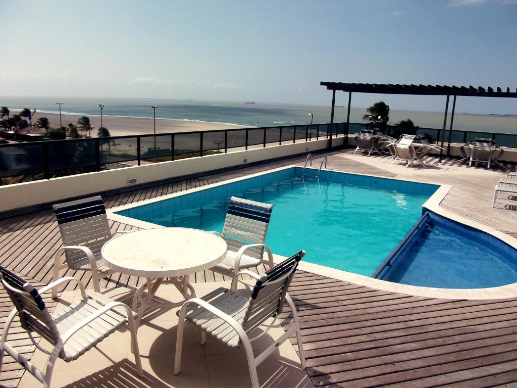 eine Terrasse mit einem Tisch und Stühlen sowie einem Pool in der Unterkunft Calhau Praia Hotel in São Luís