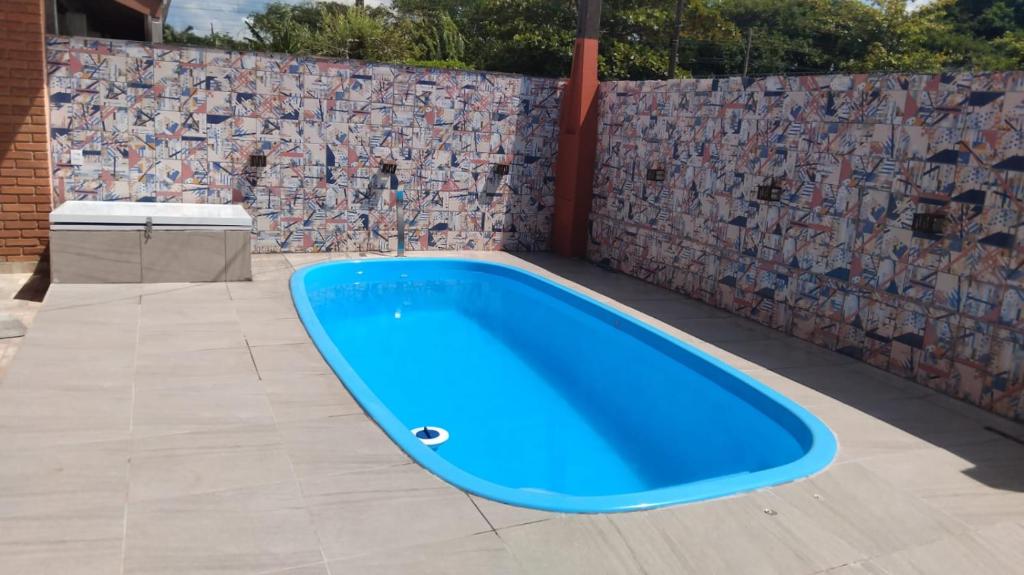 a blue hot tub on a patio with a stone wall at Casa com Piscina Balneário Oásis - Quadriciclo in Peruíbe