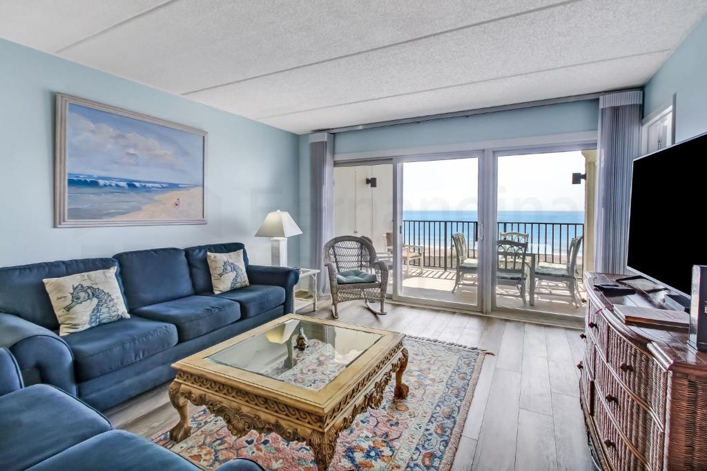 a living room with a blue couch and a tv at Striking Oceanview Condo in Fernandina Beach