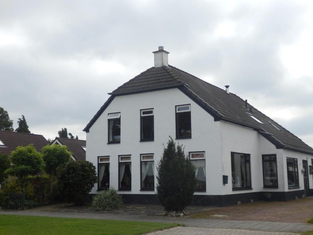 a white house with a black roof at Bed & Breakfast de Runde in Emmer-Compascuum
