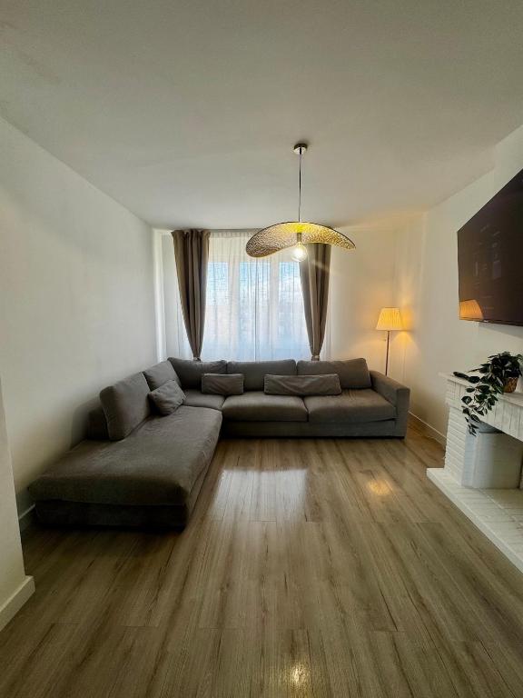 - un salon avec un grand canapé et une grande fenêtre dans l'établissement Cozy 2 bedrooms, à Dunkerque