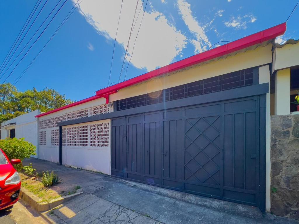 un garaje con una puerta de garaje negra en una casa en Casa de Helen, en Antiguo Cuscatlán
