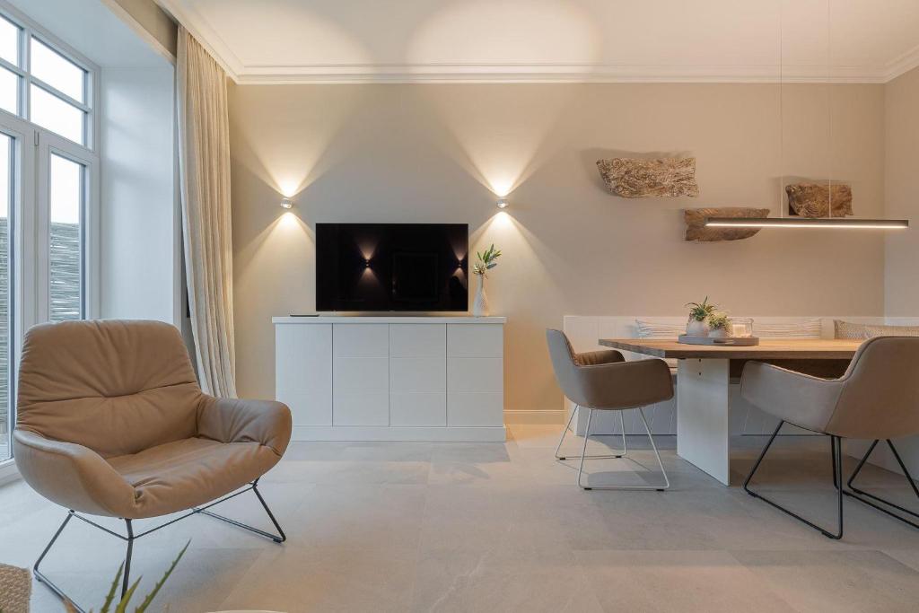 a living room with a table and a tv on a wall at Ocean-Breeze-1 in Wenningstedt