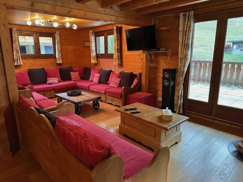 - un salon avec des canapés rouges et une télévision dans l'établissement Chalet spacieux 15 pers, proche remontées, balcon, terrasse - FR-1-676-208, à Châtel