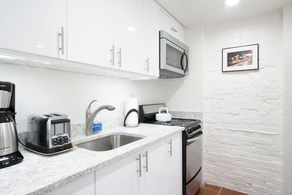 a white kitchen with a sink and a microwave at WELL-EQUIPPED STUDIO APT - WALK TO METRO SUBWAY in Washington, D.C.