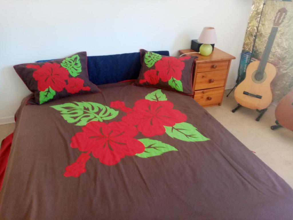 Un dormitorio con una cama con flores rojas. en One, en La Plaine-des-Palmistes