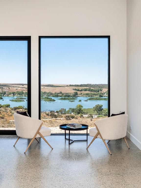two chairs and a coffee table in a room with large windows at Riverstone Retreat in Mannum