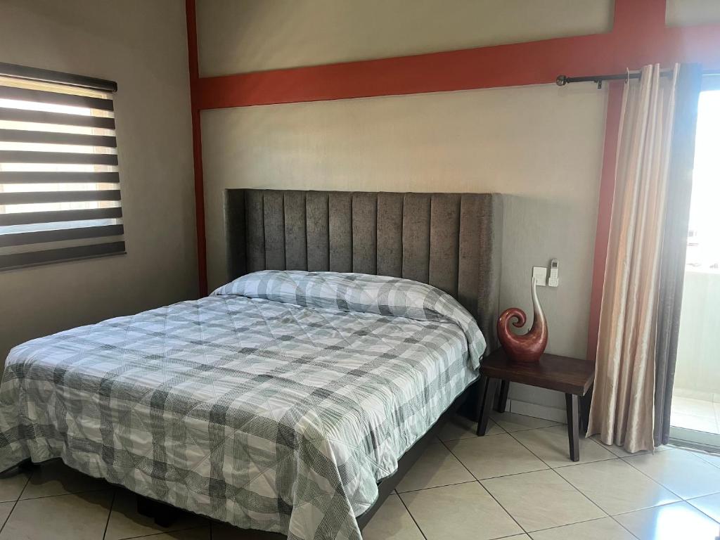 ein Schlafzimmer mit einem Bett mit einer gestreiften Decke in der Unterkunft Departamentos la Roca D4 in La Peñita de Jaltemba