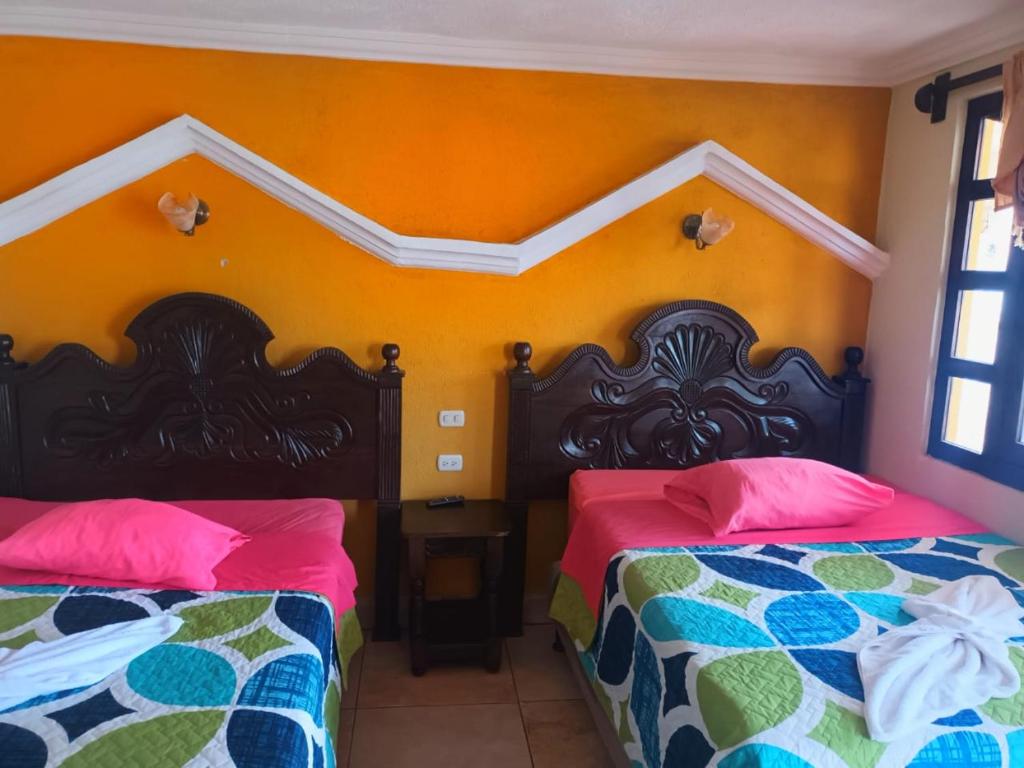 two beds sitting next to each other in a room at Hotel TINAMIT in San Pedro La Laguna