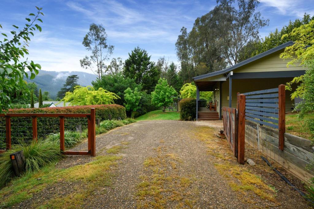 a house with a fence next to a driveway at Houghs Cabin in Bright