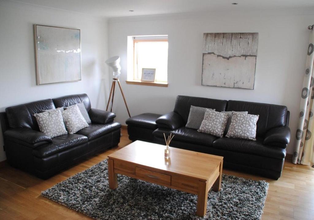 a living room with a black leather couch and a coffee table at Executive 3 Bed Apartment Aberdeen in Aberdeen