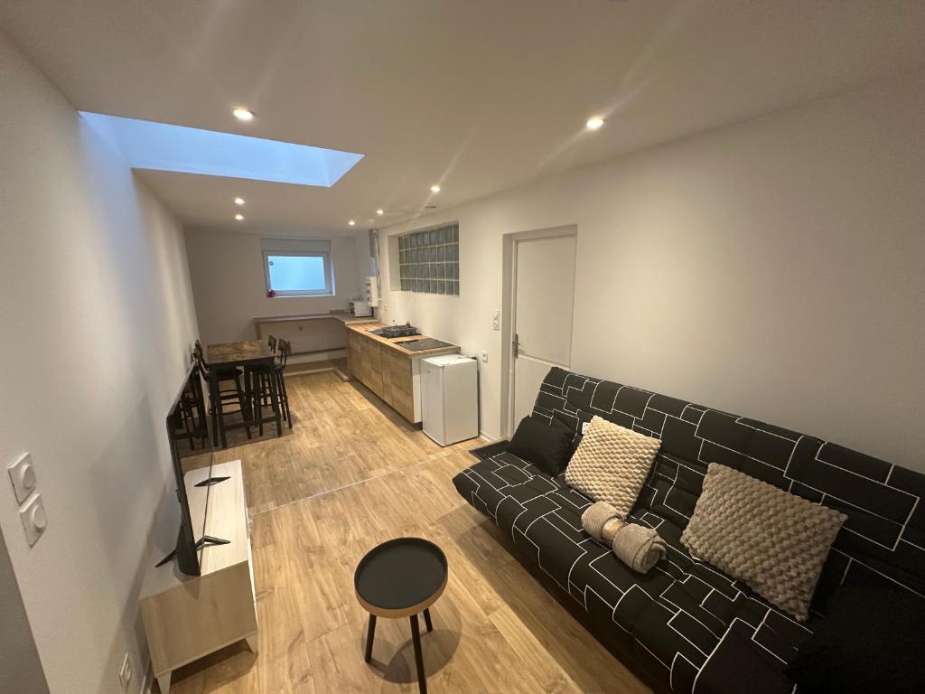 a living room with a black couch and a kitchen at 2 chambres pour 6 pers proche plage et cap gris nez in Calais