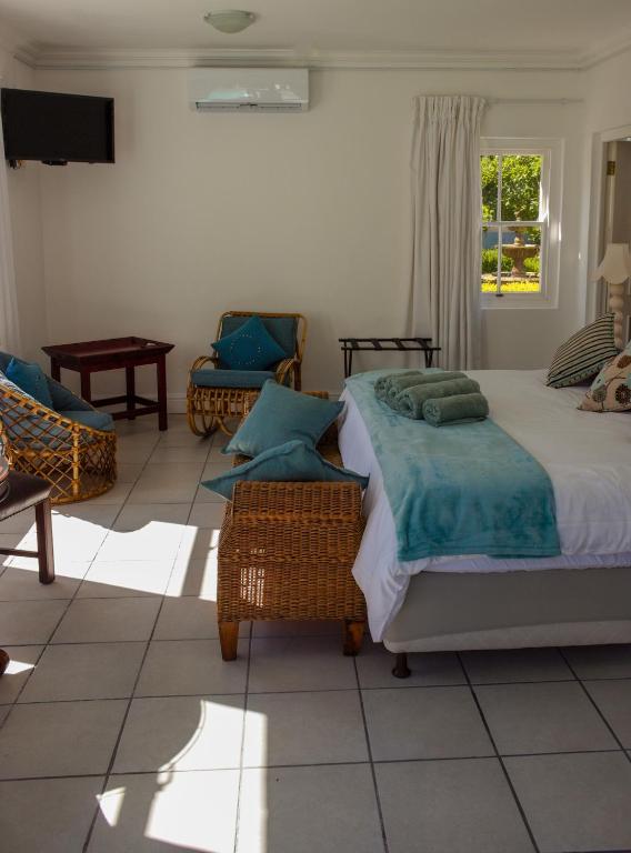 una camera con letto, sedie e TV di Tsitsikamma Mountain View Lodge a Stormsrivier