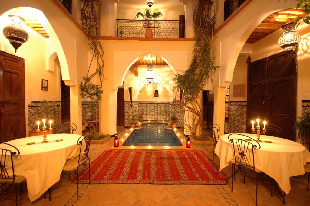 a room with two tables and a pool in the middle at Riad El Sagaya in Marrakech