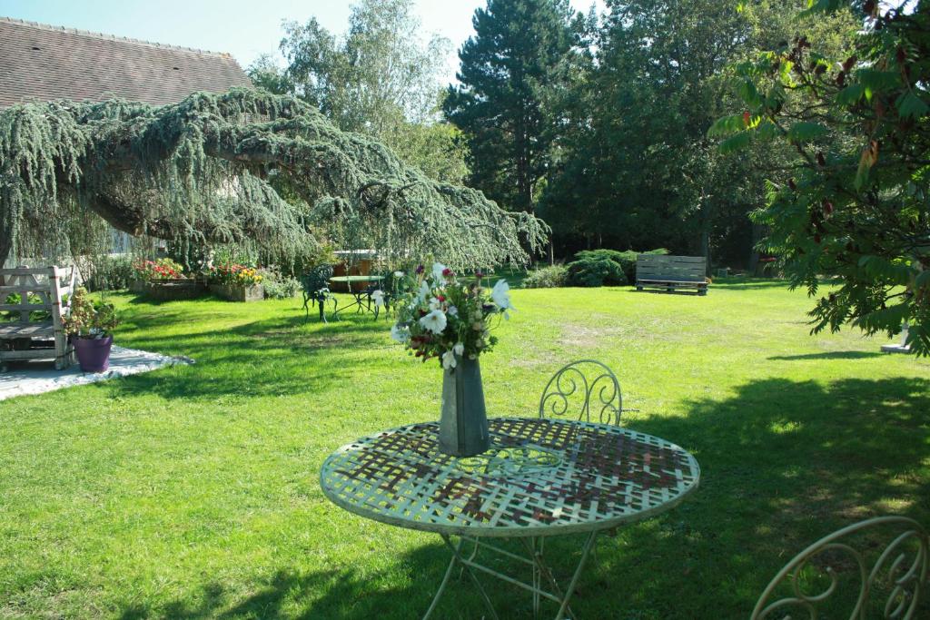 un tavolo con un vaso di fiori sopra in un giardino di Maison Prairie Bonheur a Magny-les-Hameaux