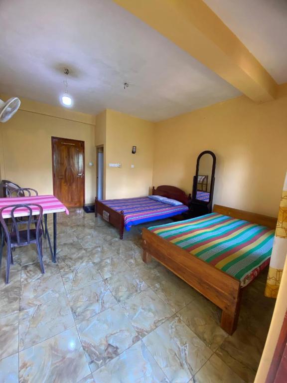a room with two beds and a table in it at Relax mountain guest house in Badulla