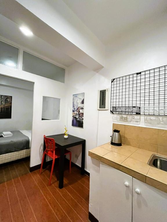 a kitchen with a table and a bed in a room at BGC Suites EDSA Makati in Manila